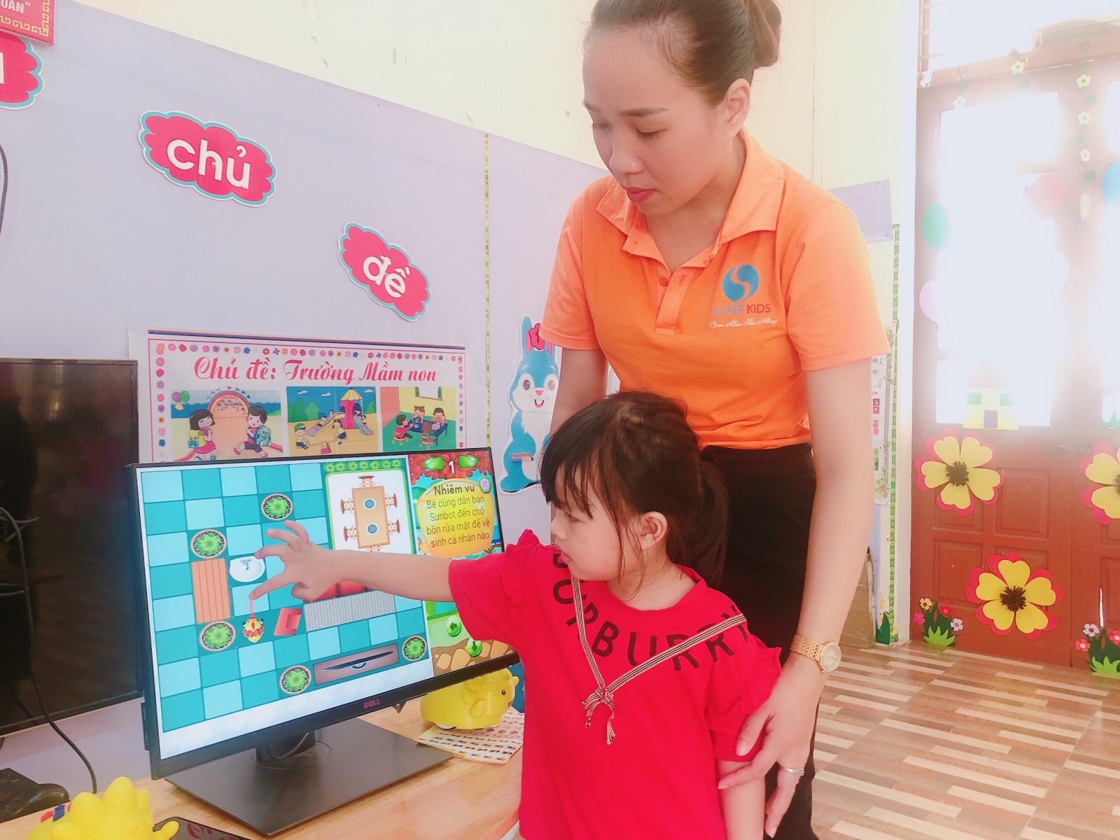 Các con đang được cô Thuý Ngần hướng dẫn thực hành trên màn hình Sunbot